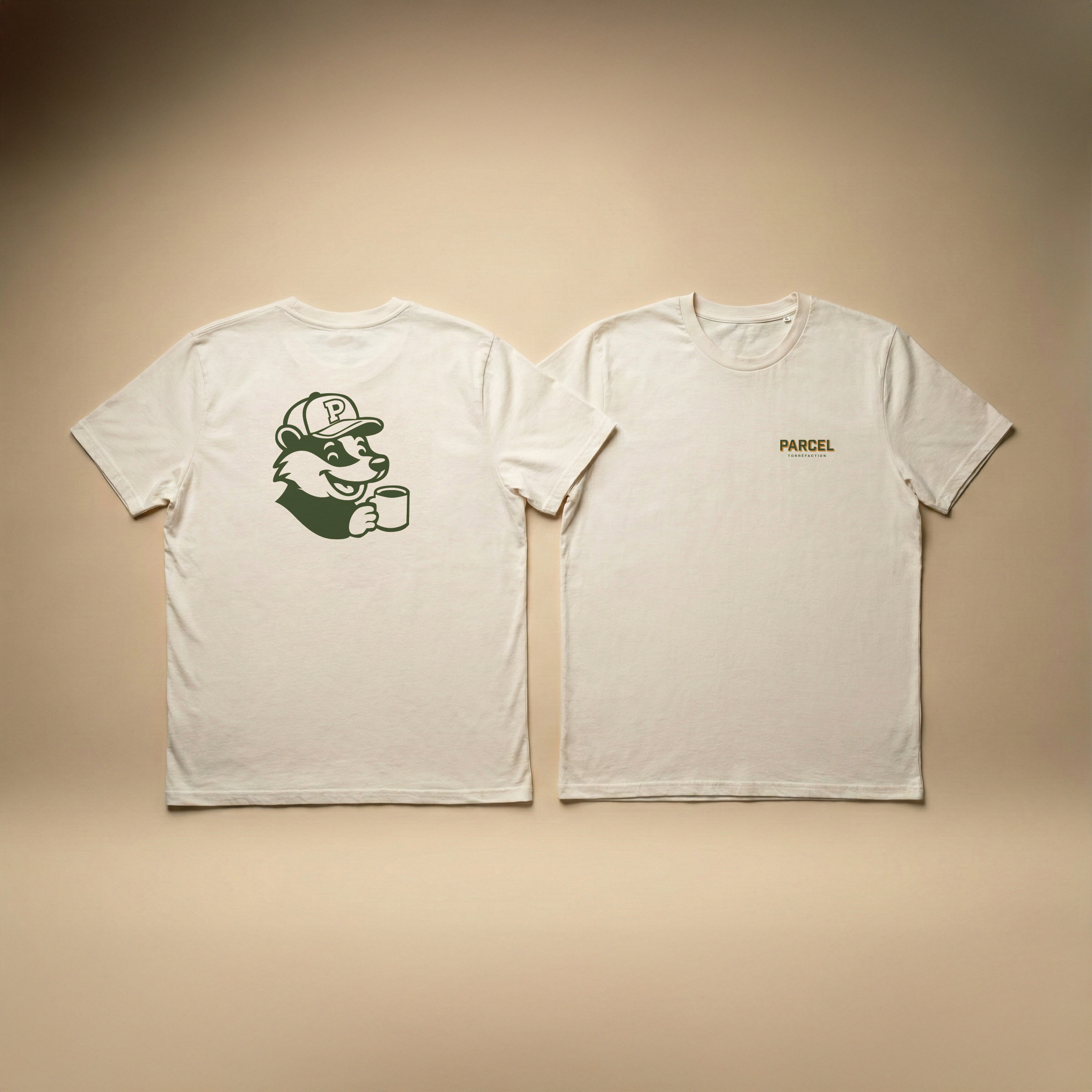 Two white Parcel Torréfaction t-shirts laid flat in a studio setup, showing the back with the mascot graphic and the front with a small chest logo, photographed on a warm beige background with soft, even lighting.